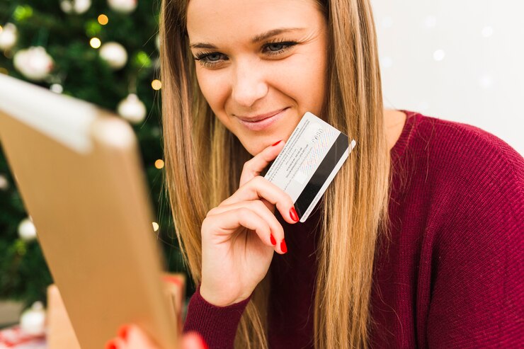 young-smiling-lady-with-tablet-plastic-card-near-christmas-tree_23-2147973988